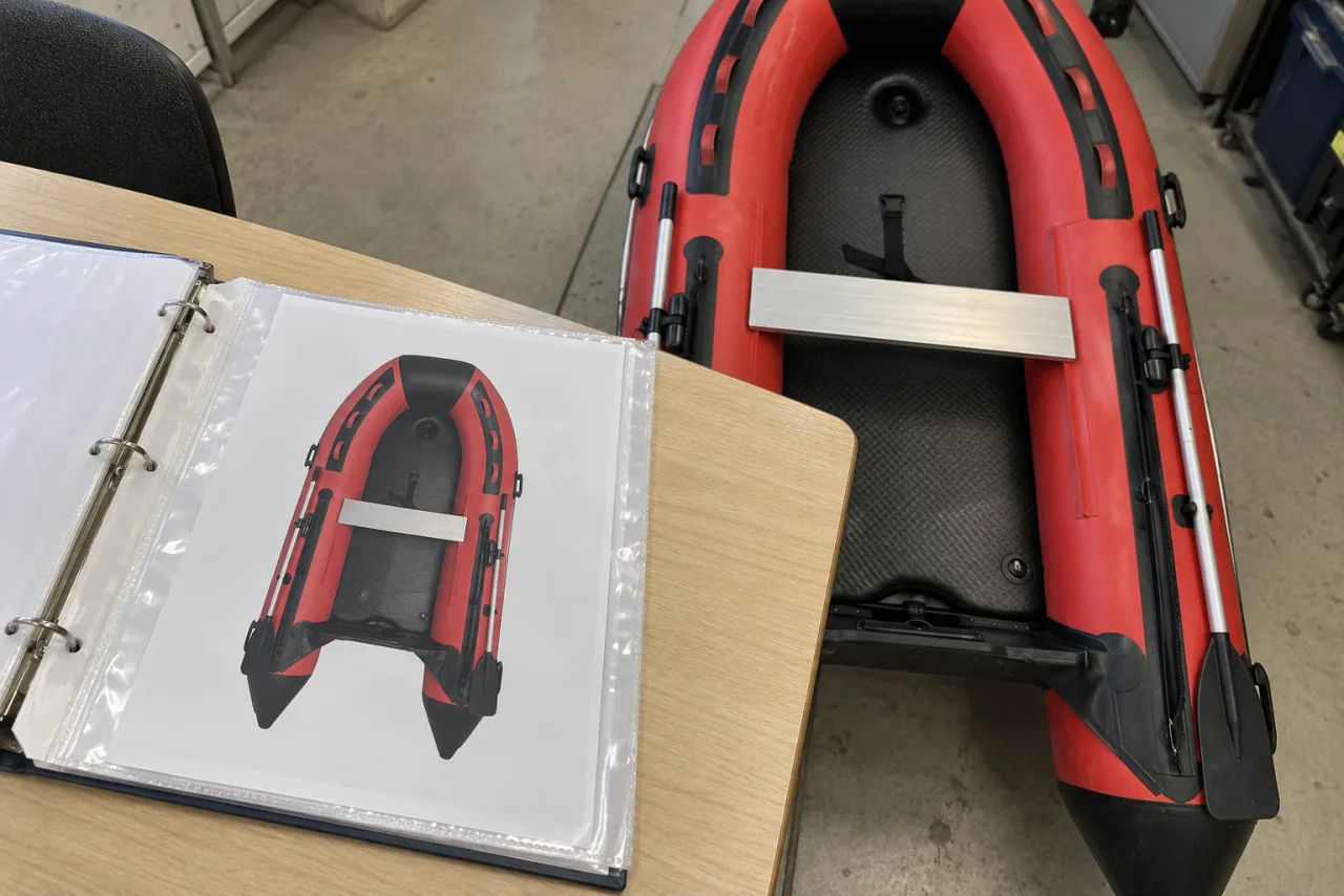 Red boat photograph and open document sleeves beside the hull